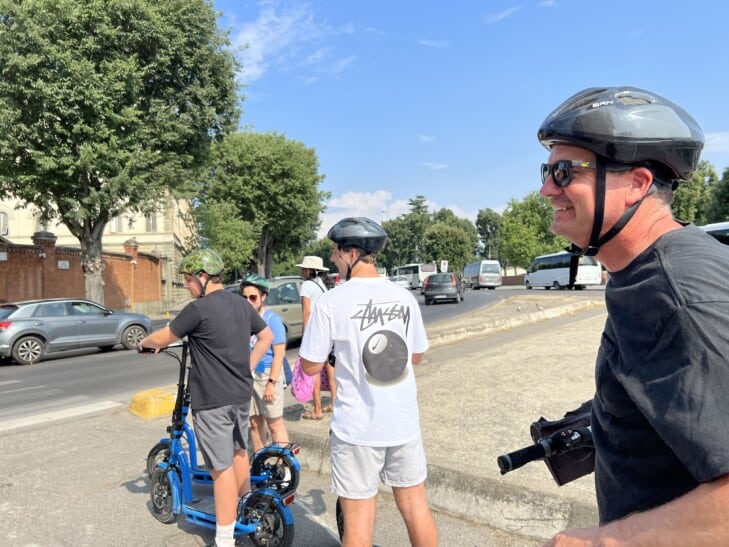 A family of three ride e-scooters through Florence, Italy