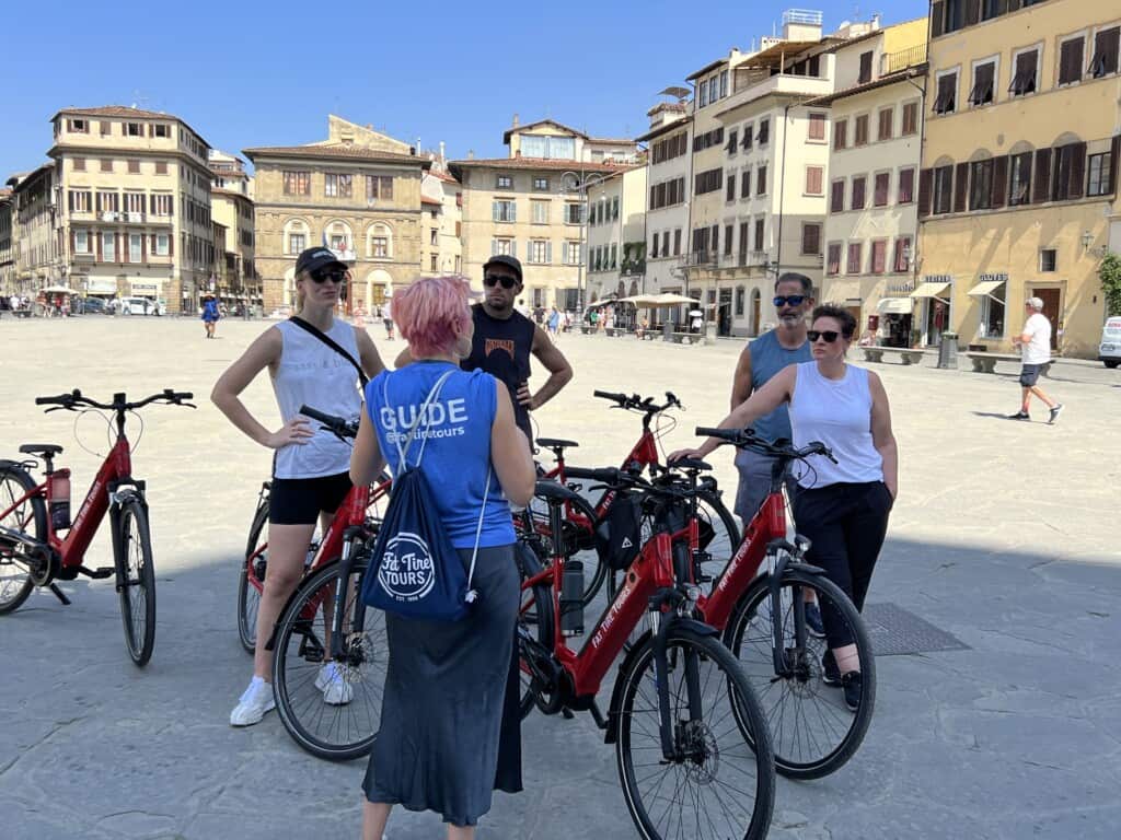 A group of 4 listens to the guide during an e-bike tour in Florence