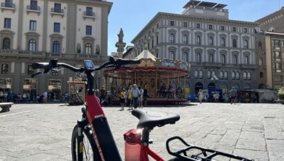 A carousel in a piazza in Italy with a red e-bike in the foreground