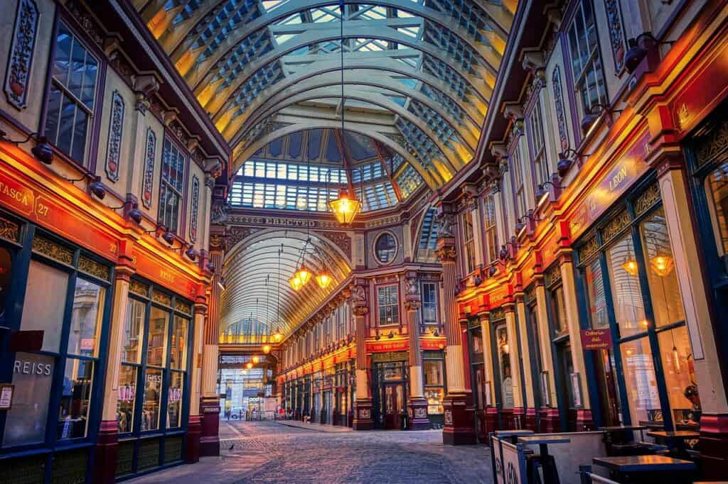 A view inside London's Leadenhall Market lit up with evening lights suspended from the roof and hanging over shops