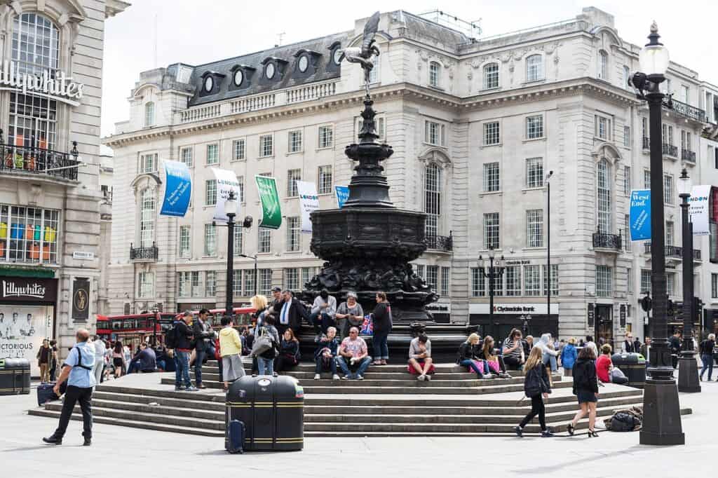London's Piccadilly Circus is pictured with people sitting around the fountain beneath the winged statue