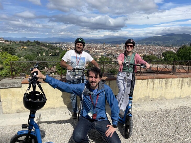 A group of two and the tour guide smile for a photo in Piazzale Michelangelo