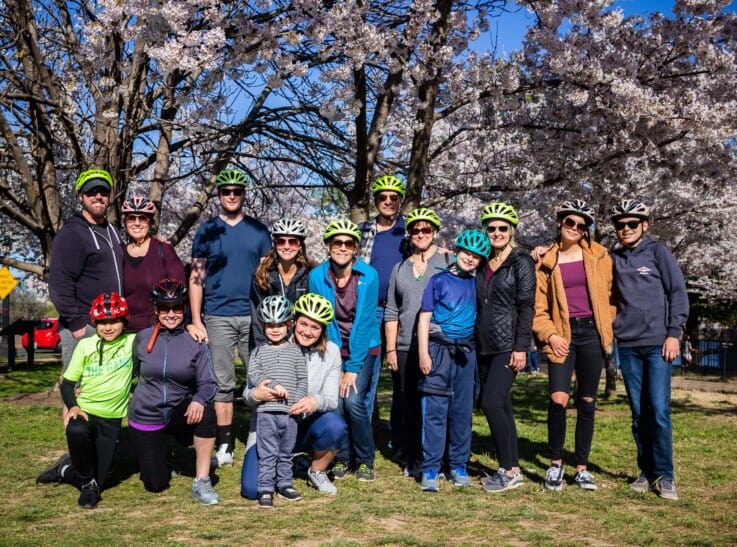 A group of cyclists pose for a photo in front of the Cherry Blossoms