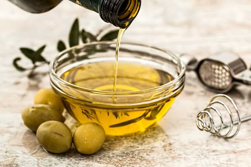 Olive oil is being poured into a small bowl