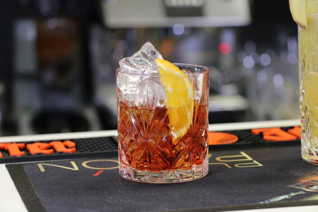 A Negroni cocktail sitting on a bar on top of a black mat