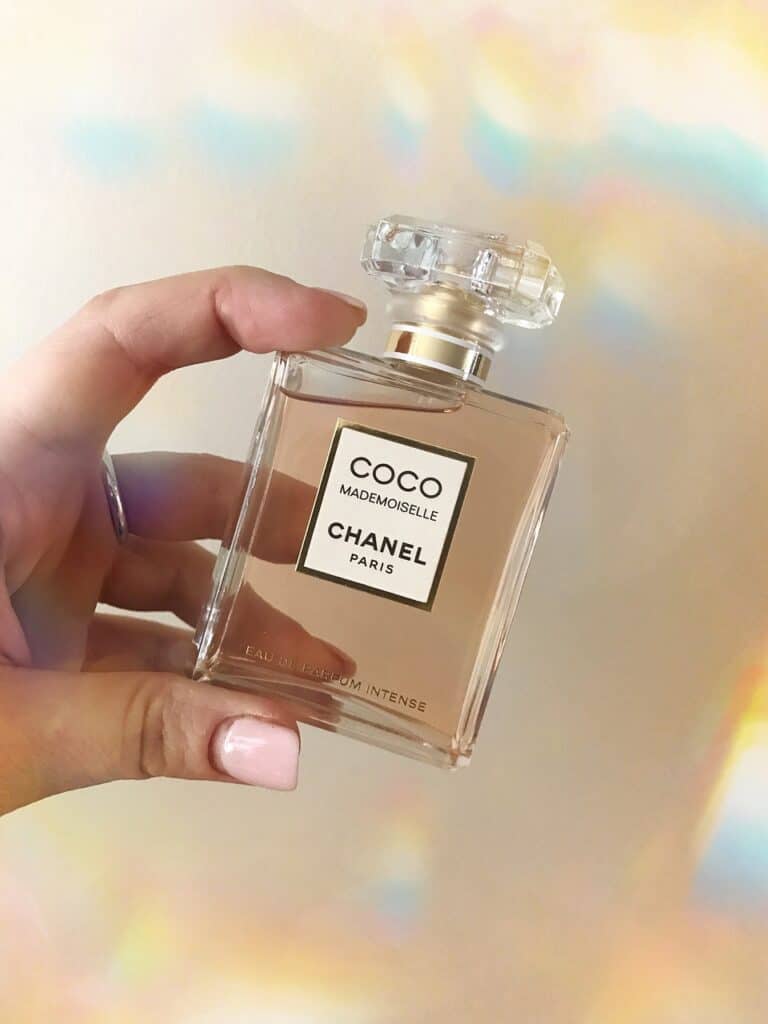 A Coco Mademoiselle Chanel perfume bottle held by a person with fingernails painted pink