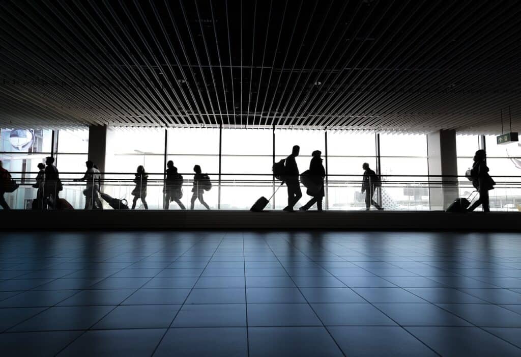 Travelers on a moving walkway with suitcases at an airport