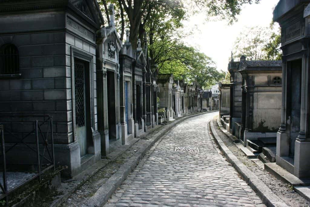 Père Lachaise cemetery pictured with a cobblestone road and graves on each side