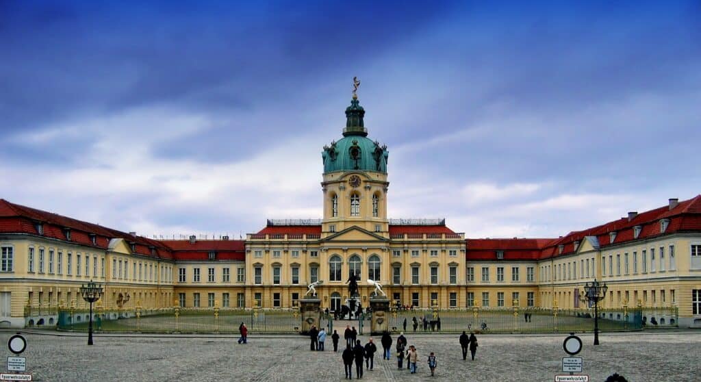 Charlottenburg Palace is pictured with tourists entering at the front gate and a deep blue sky overhead