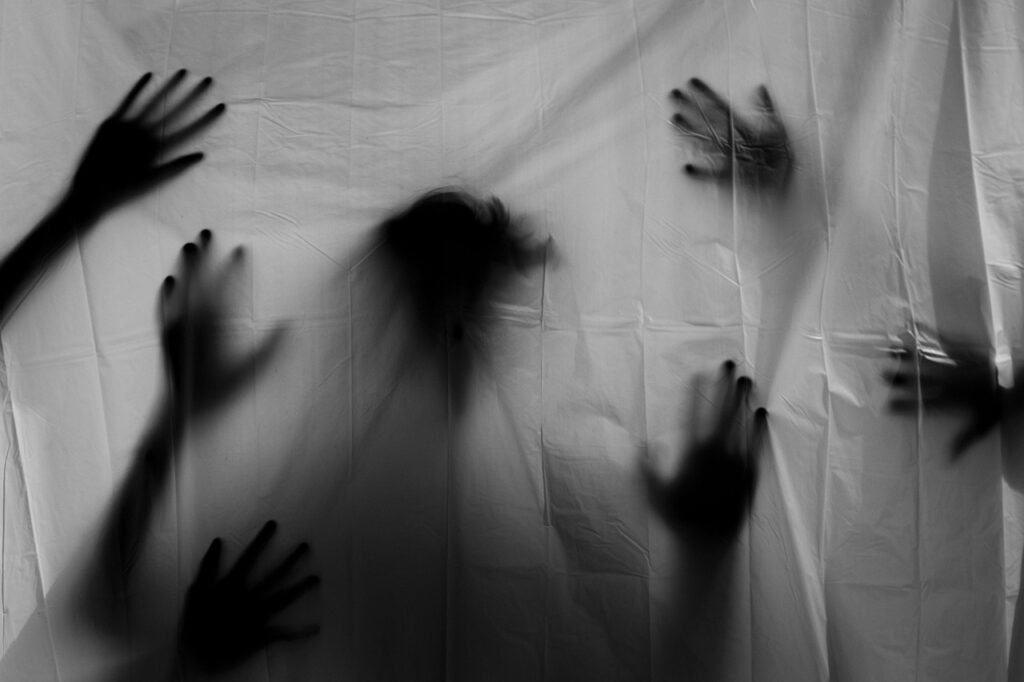 A spooky silhouette of hands behind a screen