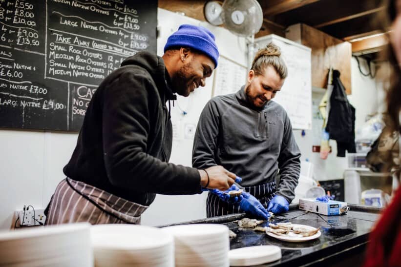 Two men shuck oysters