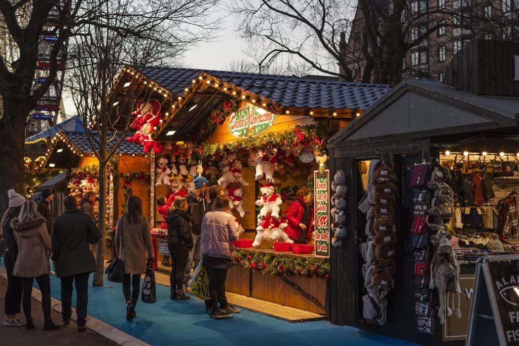 A scene from a Christmas market where people are shopping and looking at teddy bears