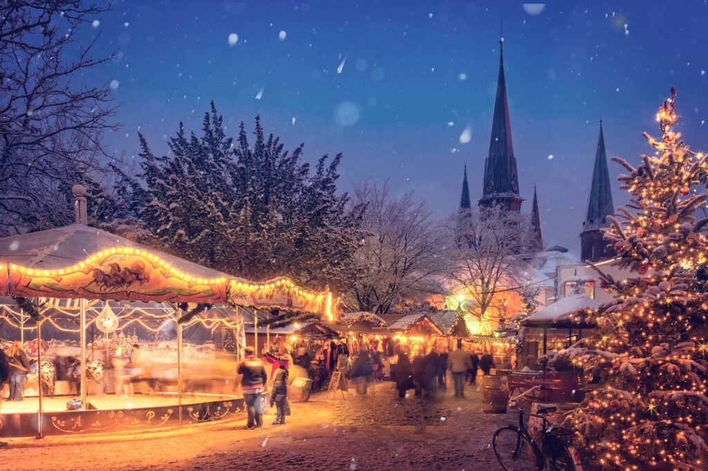 An outdoor Christmas market as snow falls down