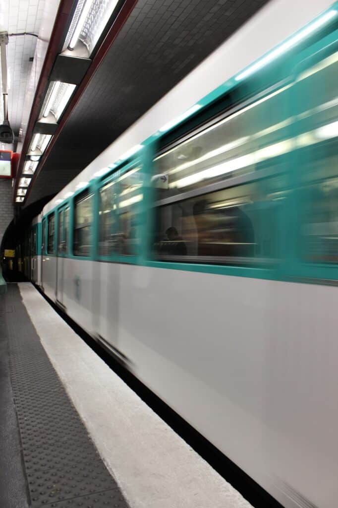 A Paris metro train with green windows and a white base going quickly by underground