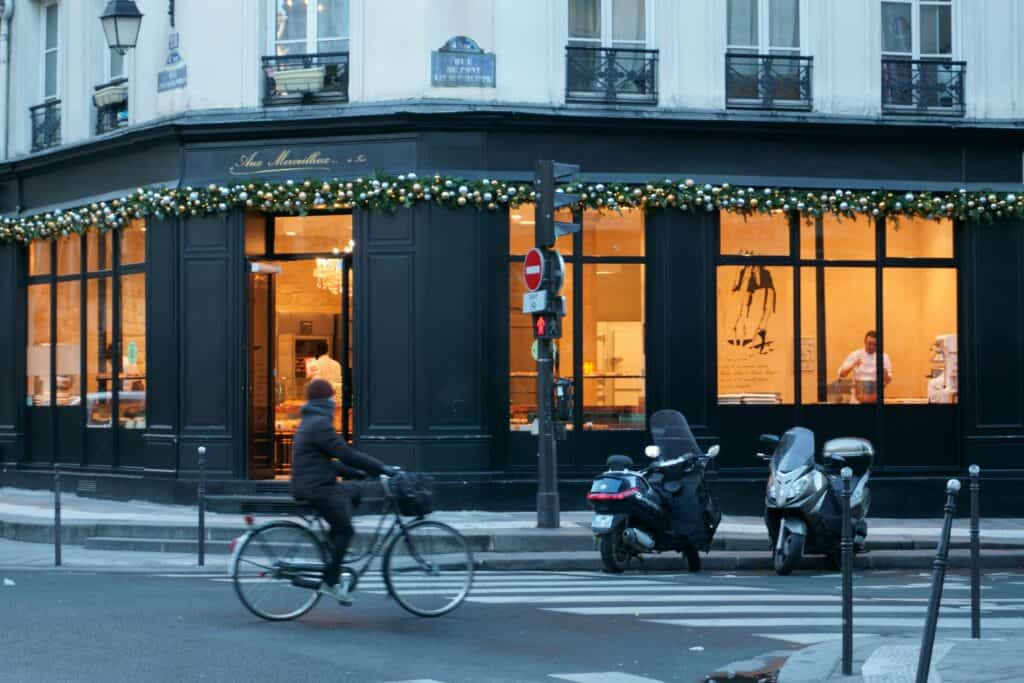A man rides a bicycle in front of a bakery in Paris, France