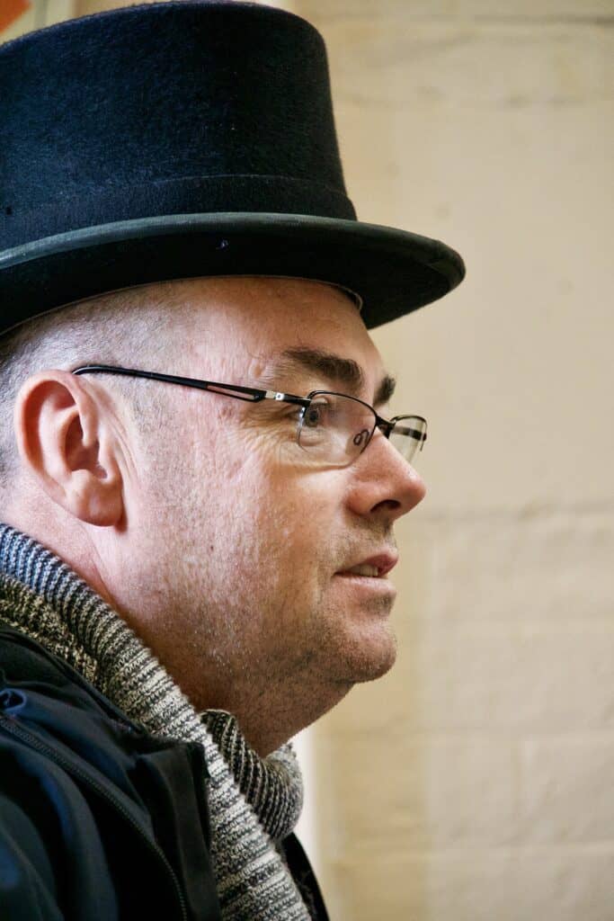 White man wearing a top hat and glasses