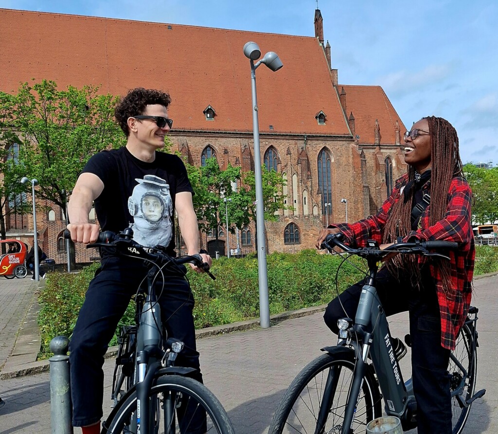 A couple on e-bikes smile at each other in Berlin