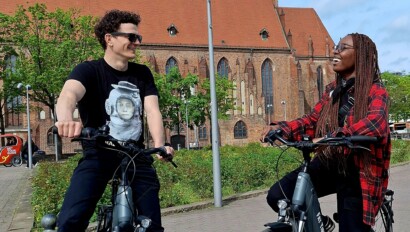 A couple on e-bikes smile at each other in Berlin