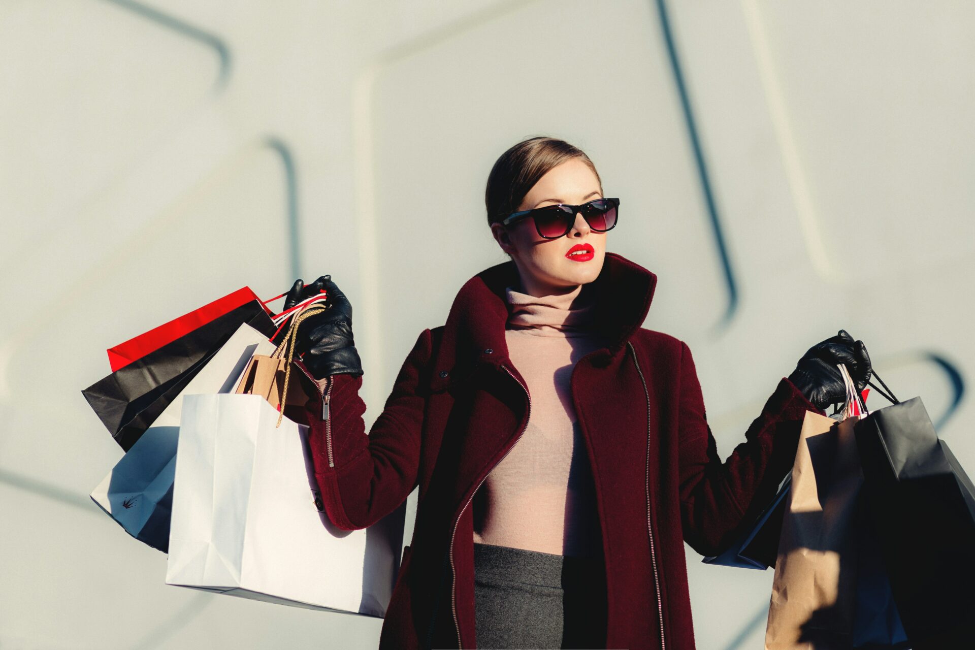 Woman wearing sunglasses holds multiple shopping bags