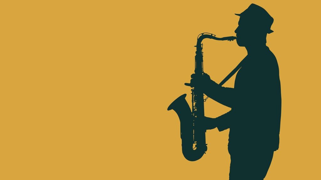 Man plays the saxophone with a yellow backdrop