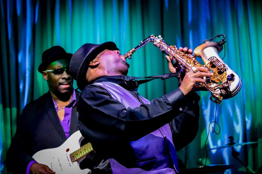 Black jazz musician plays the saxophone while wearing a hat