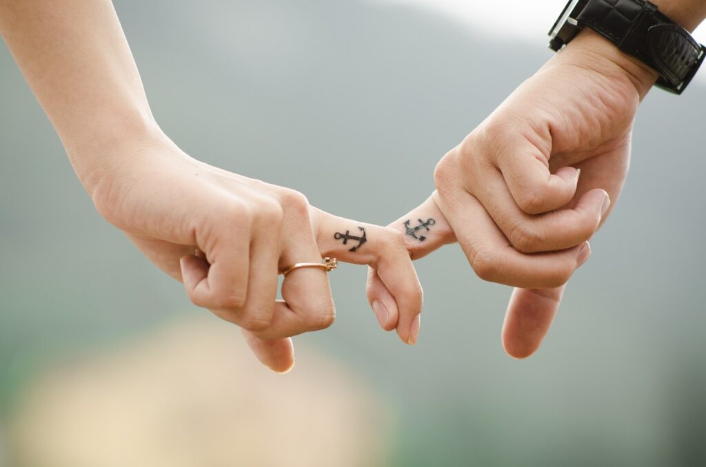 two people holding fingers with anchors tattooed on their index fingers