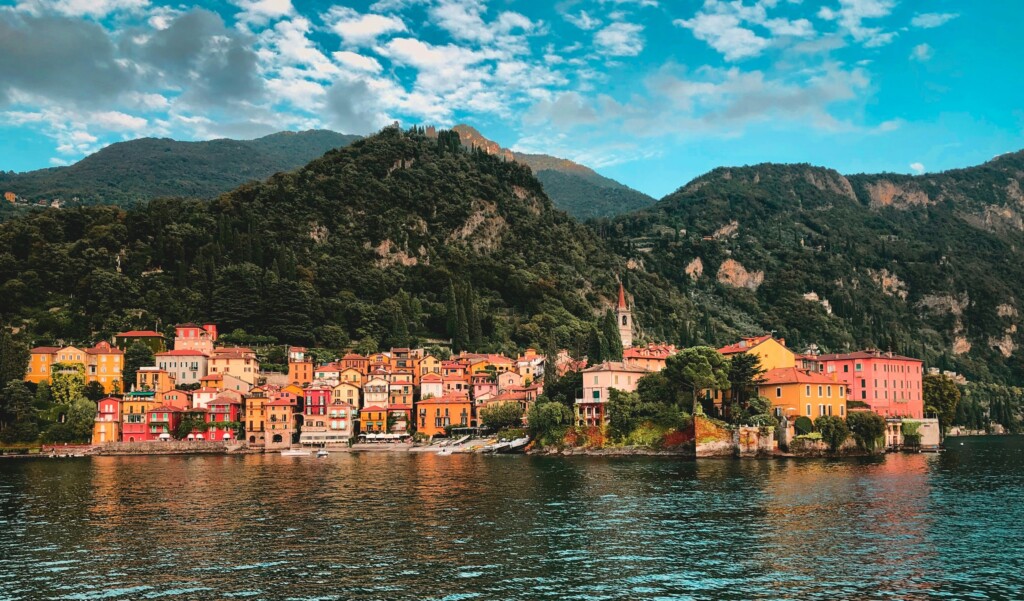 Yellow and orange houses along the edge of Lake Como with hills in the background