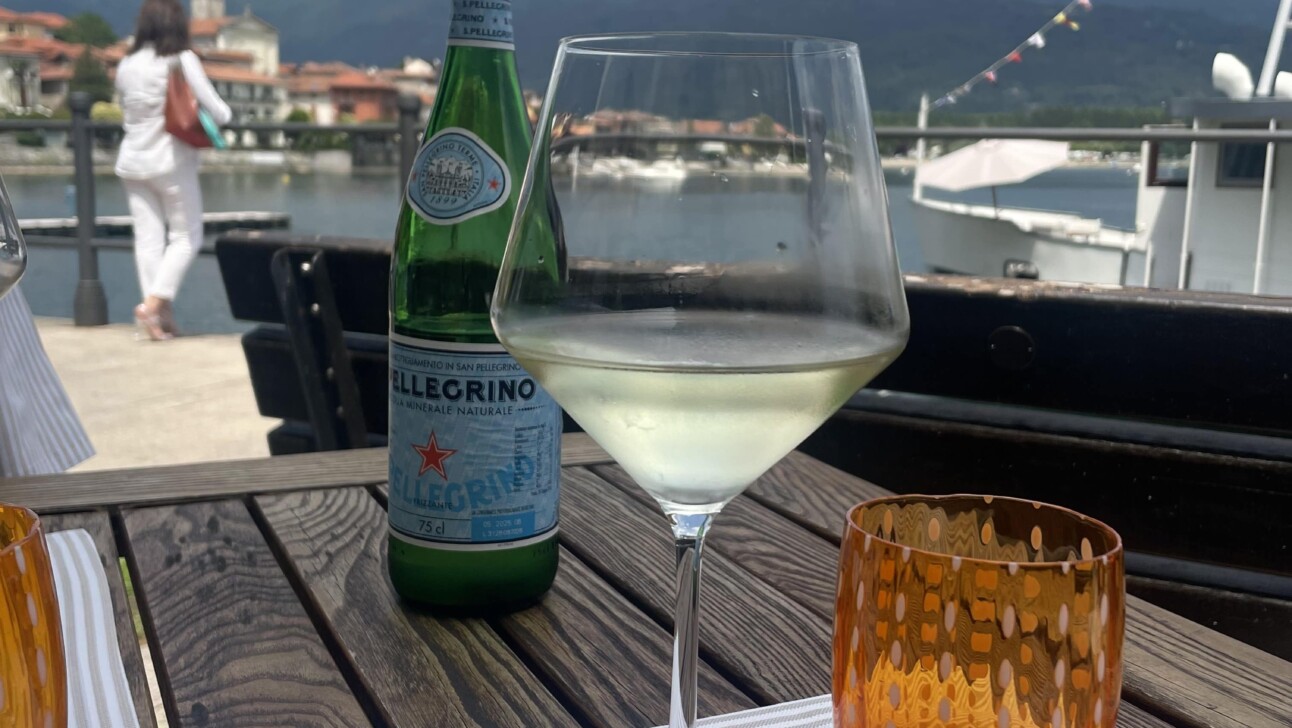 A glass of white wine and a bottle of San Pellegrino at a lakeside eatery on Lake Maggiore