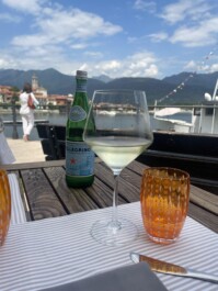 A glass of white wine and a bottle of San Pellegrino at a lakeside eatery on Lake Maggiore