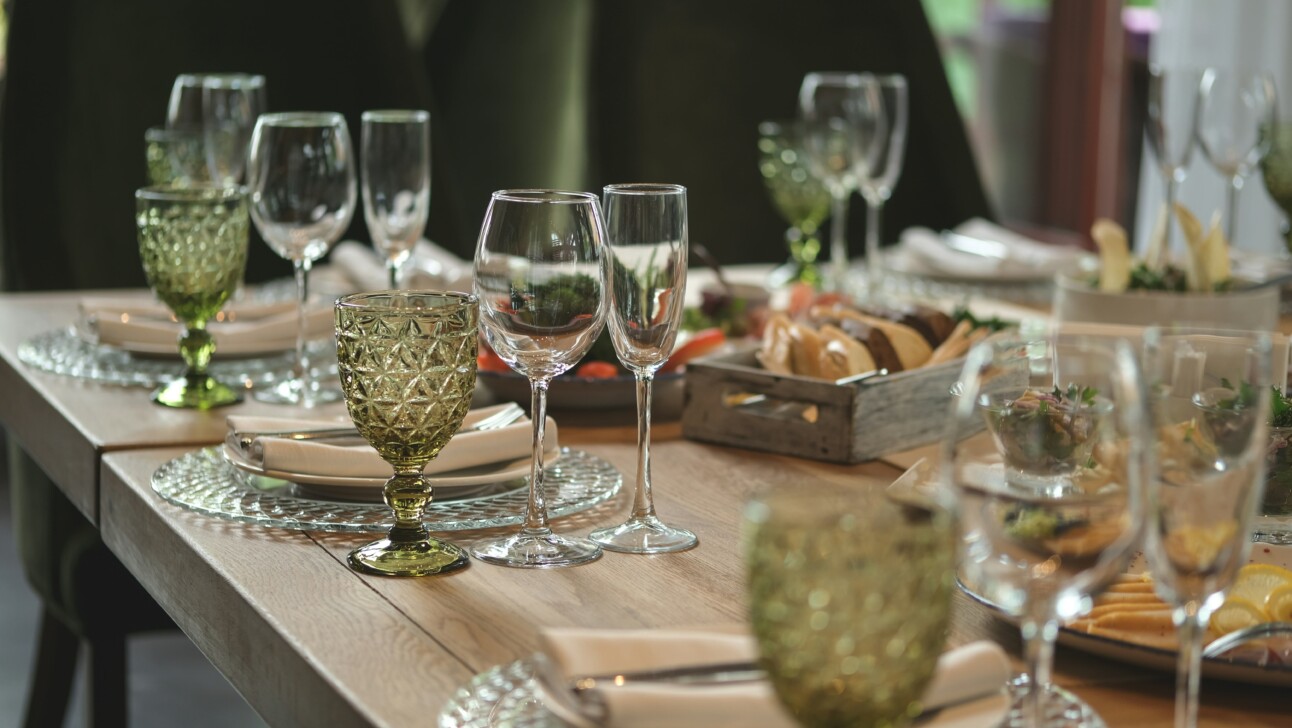 A wooden table set with wine glasses and plates.